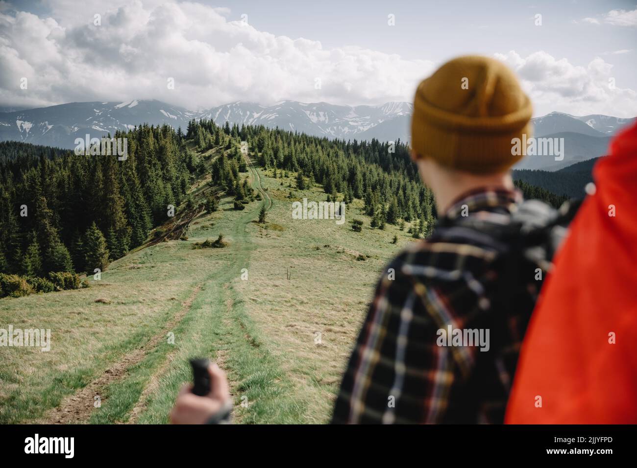 A tourist with backpack on the mountains road. Green spring mountains on the background. Landscape photography Stock Photo