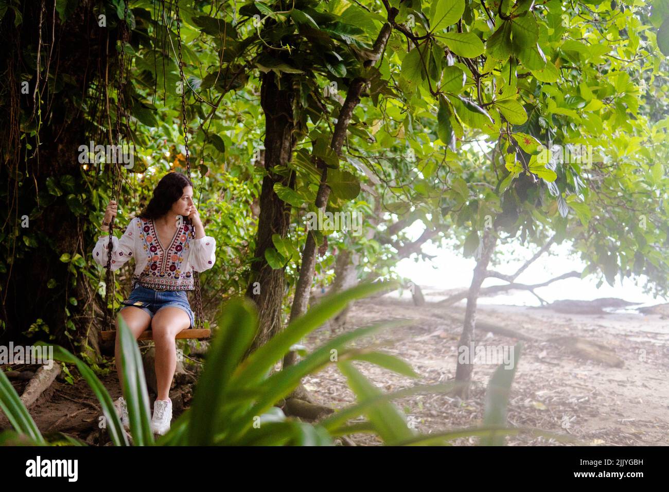woman sitting on a swing in the jungle of Costa Rica Stock Photo