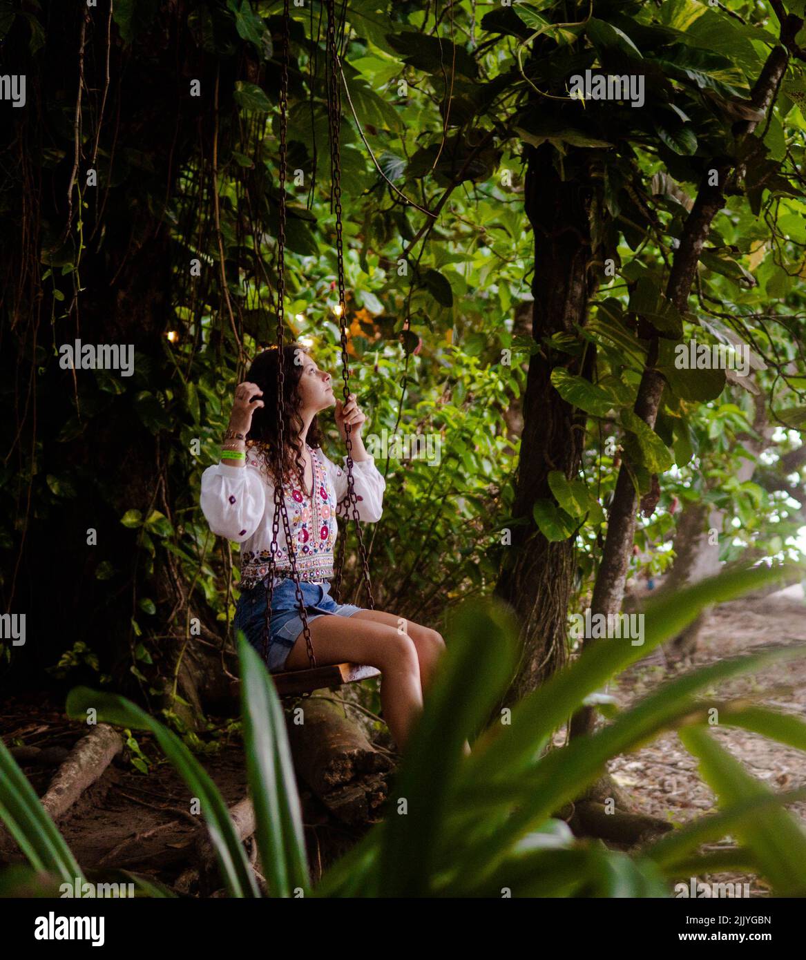 woman sitting on a swing in the jungle of Costa Rica Stock Photo