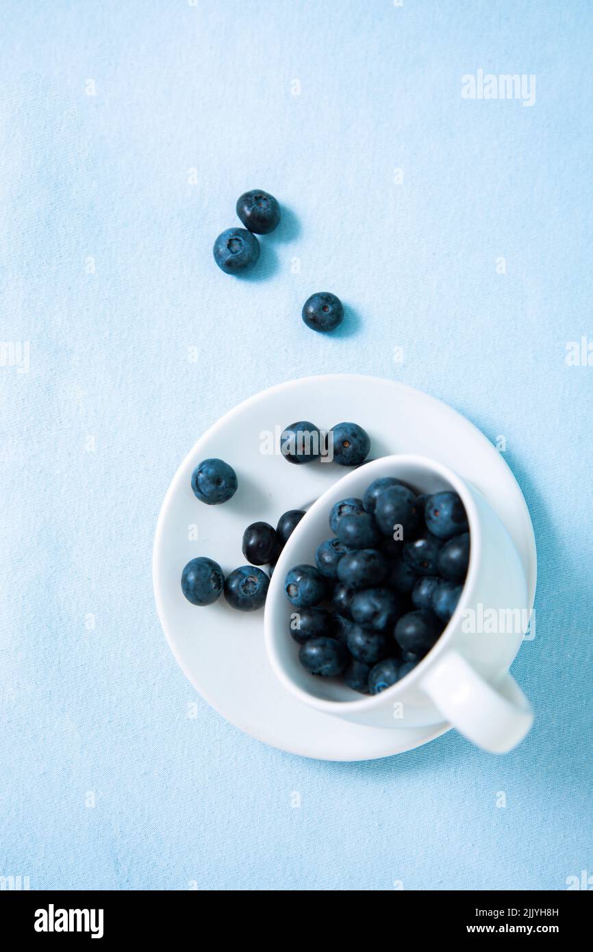 Vertical photo with blueberries sleeping out of a teacup Stock Photo