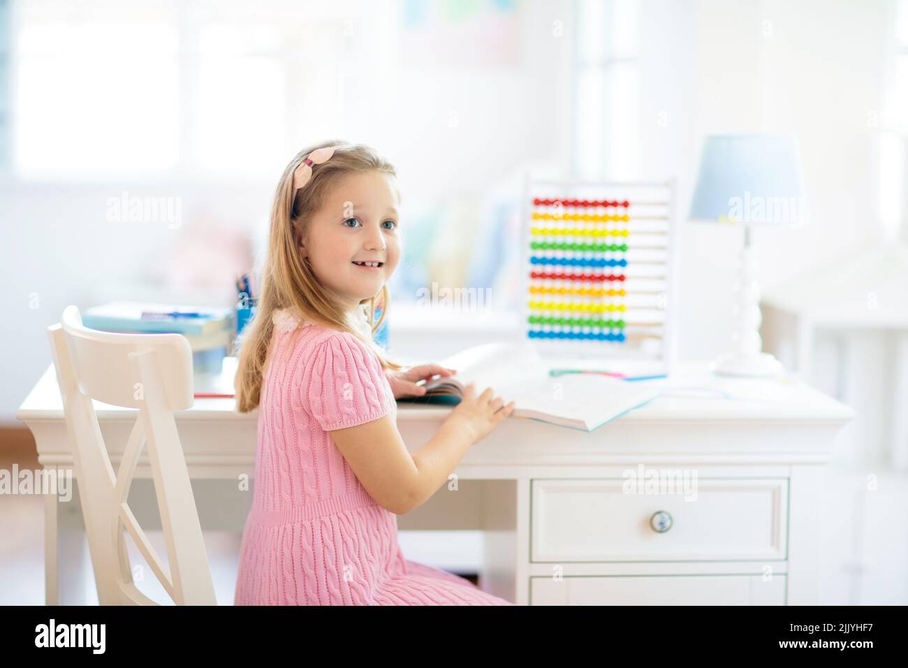 Child drawing rainbow. Kid painting at home. Little girl doing homework after school. Kids desk with abacus in white sunny bedroom. Stock Photo
