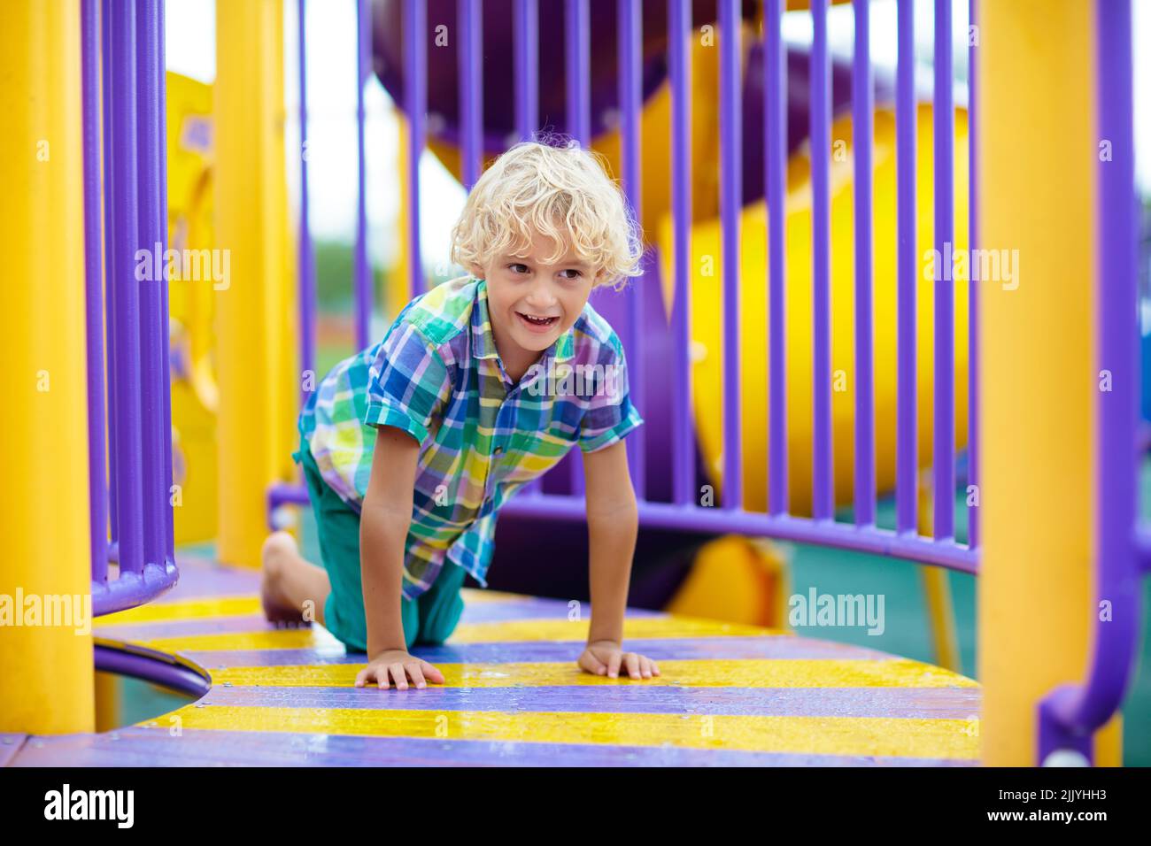 Child playing on outdoor playground. Kids play on school or kindergarten yard. Active kid on colorful slide and swing. Stock Photo