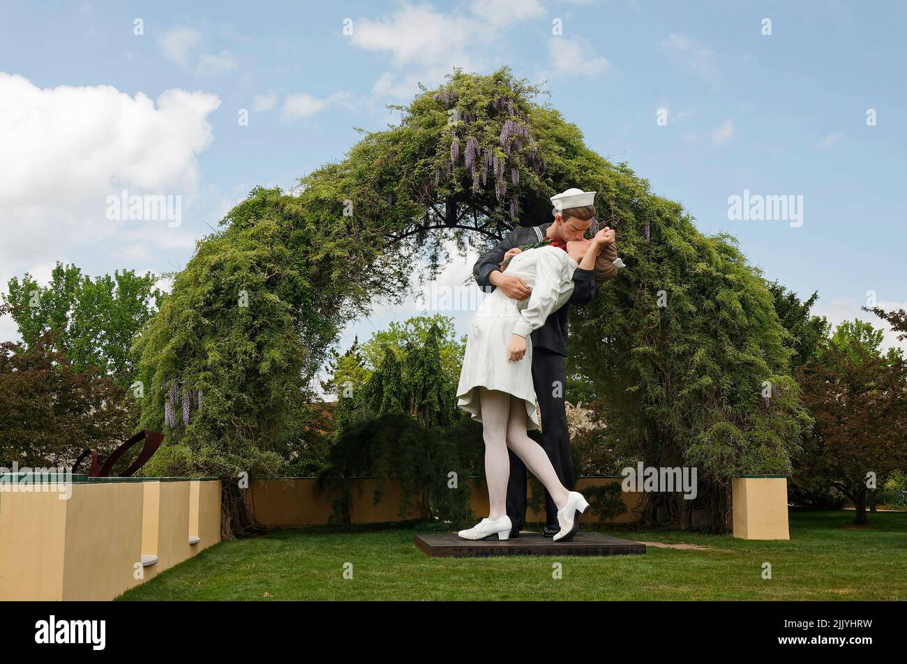 Unconditional Surrender, huge sculpture, sailor kissing nurse, wisteria, trees, grass, outdoors, Grounds for Sculpture; Seward Johnson Center for the Stock Photo
