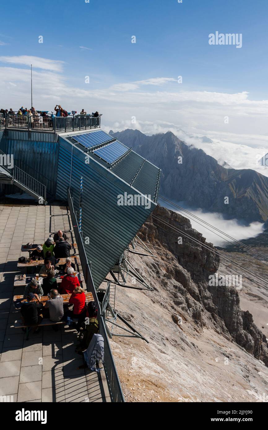 Tourists Dining at Restaurant on top of Zugspitze Mountains. Bavaria, Germany. Technical Research Centre. Telecommunications Antennas with Radar recei Stock Photo