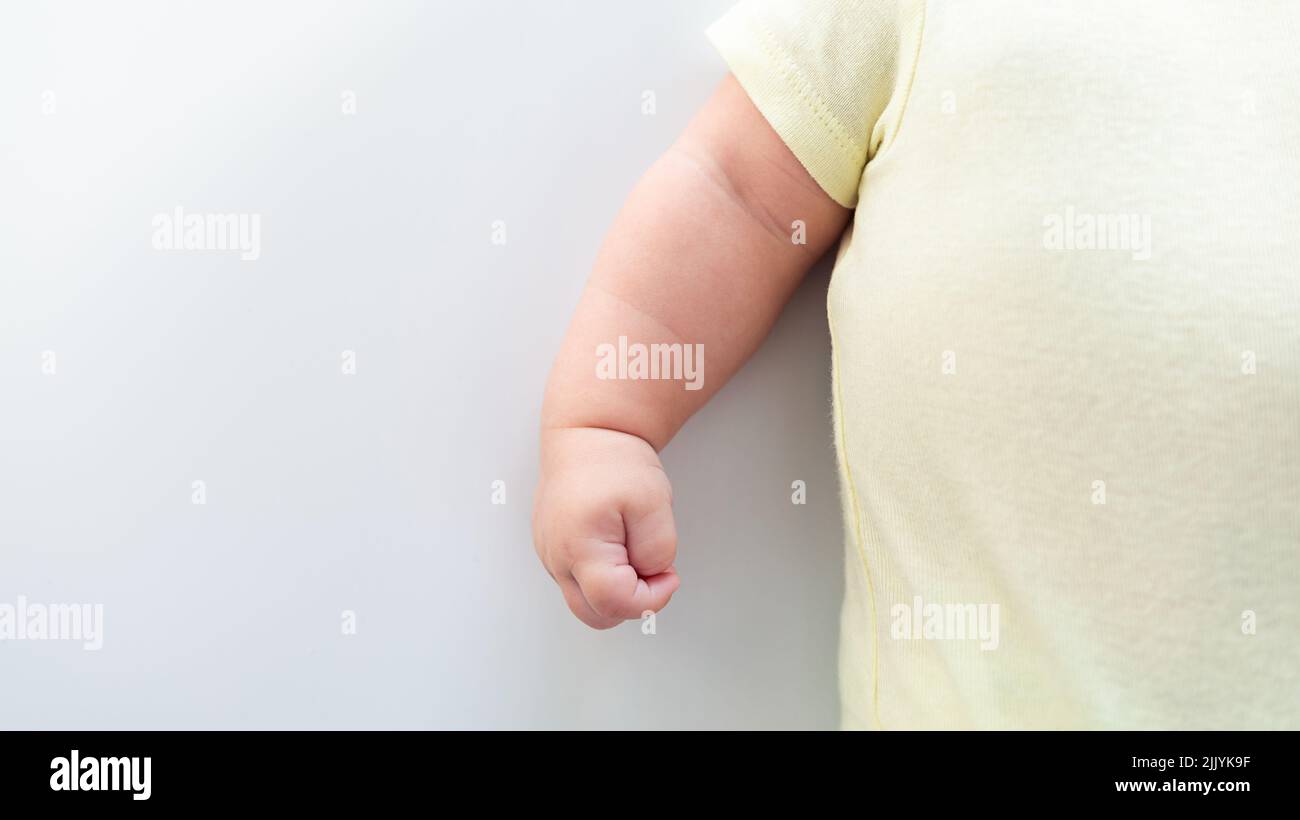 Close up of newborn boy hand on white sheet background. Baby sleeping on the bed. A beautiful conceptual image of childhood. Family and home concept w Stock Photo