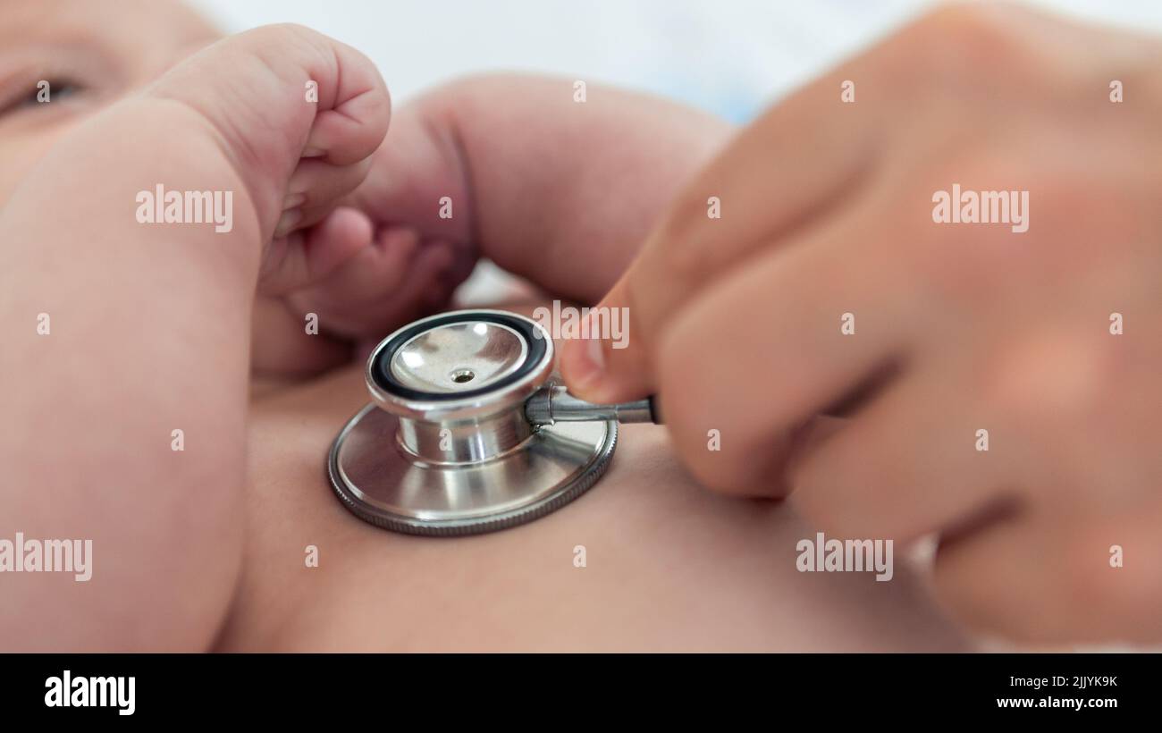 Doctor listens the heart to small newborn with stethoscope. Cute boy and chubby hands of a child. A newborn age of 3 months. Pediatrician's appointmen Stock Photo
