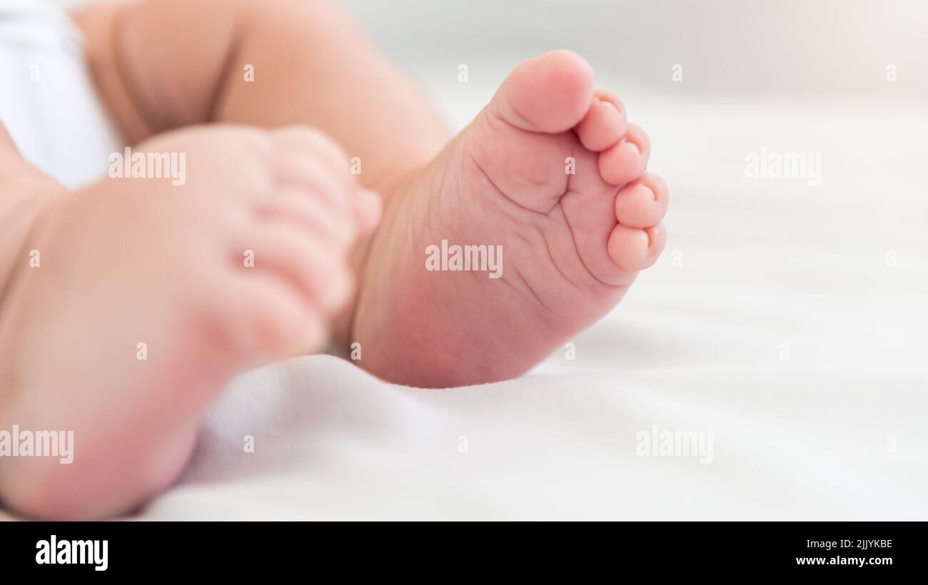 Close up little tiny baby with chubby foots over a sheets bed. Peace calm infant toddler newborn boy sleep resting take deep nap laying on soft white Stock Photo
