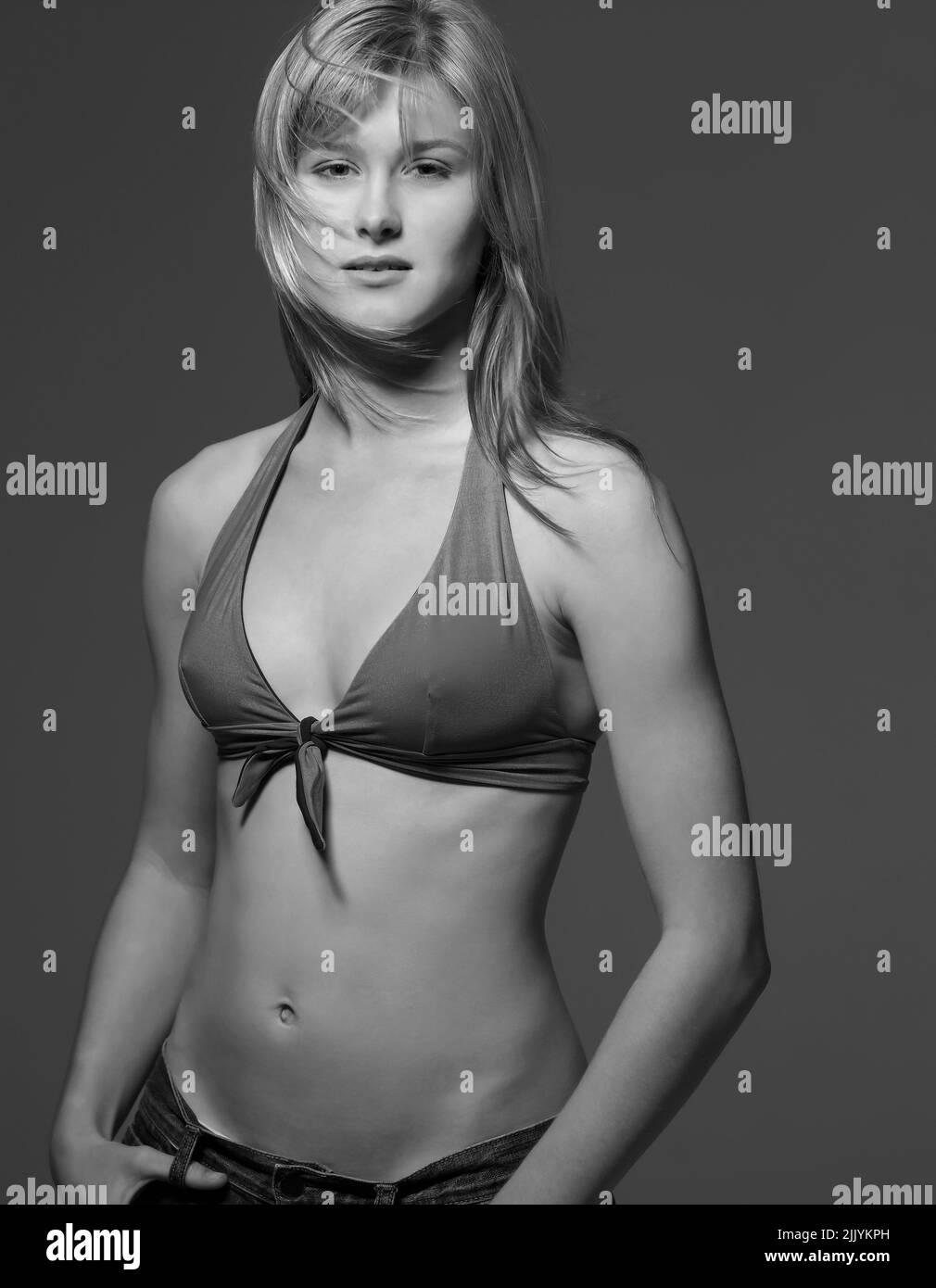 Portrait of beautiful young woman wearing bikini top and jeans - B&W Stock Photo