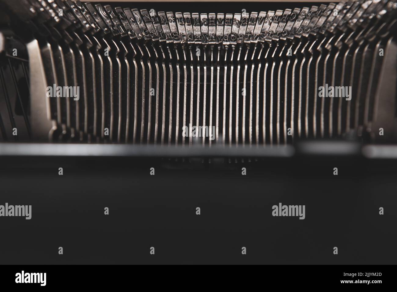 Typewriter typebars closeup with paper feeder in foreground Stock Photo