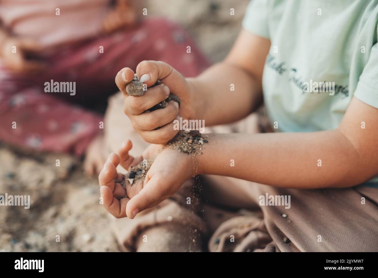 A boy's hands pouring sand from one to another. Child in happy mood, a family. Stock Photo