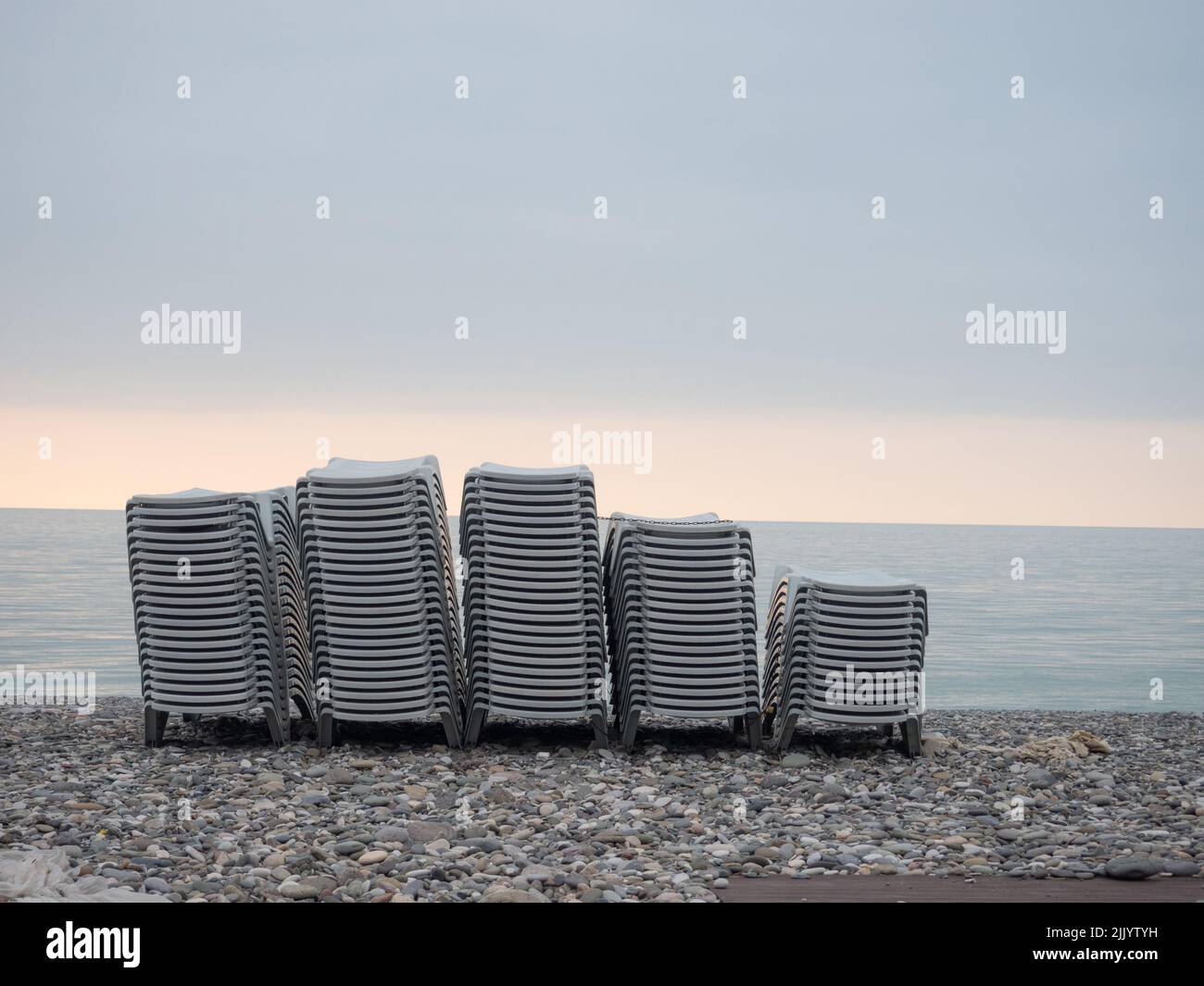 Stacked plastic sun loungers on the beach. Sunbeds in bad weather