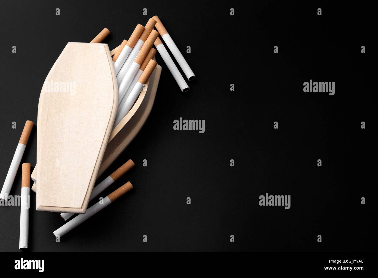 Moody image of real wood coffin filled with cigarettes in darkness with