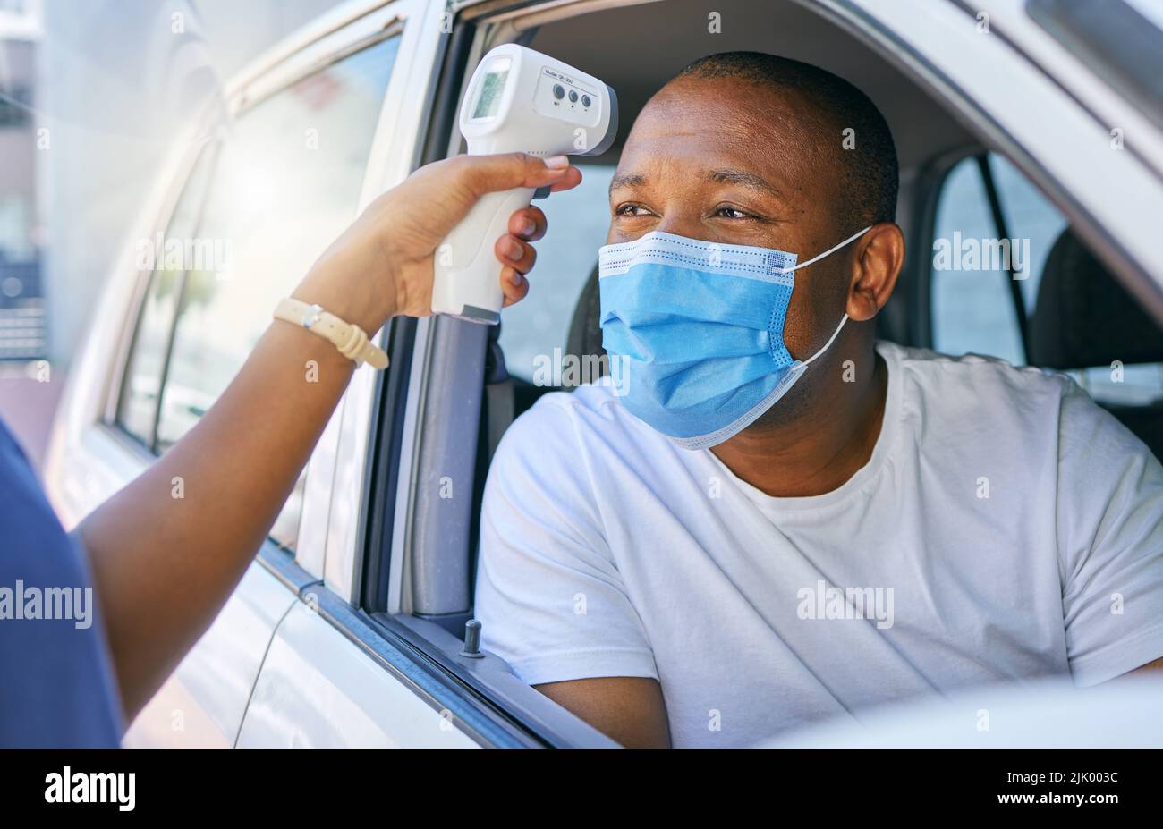 Covid, corona and infection testing site as a drive thru service station for people traveling. African man wearing a protective face mask to avoid Stock Photo