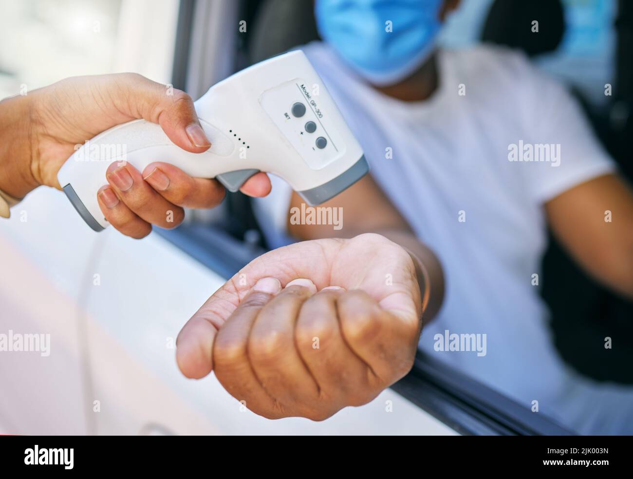 Covid, corona infection testing and scan site as a drive thru service station for people traveling. African man having his temperature taken with a Stock Photo