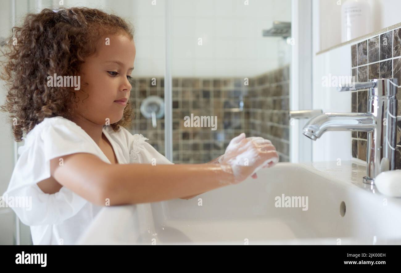 Little girl washing hands with water and soap in bathroom at home ...