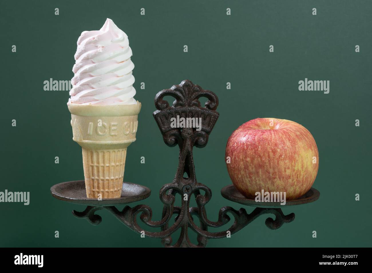 close up of ice cream cone and apple on a balanced scale concept of healthy eating Stock Photo