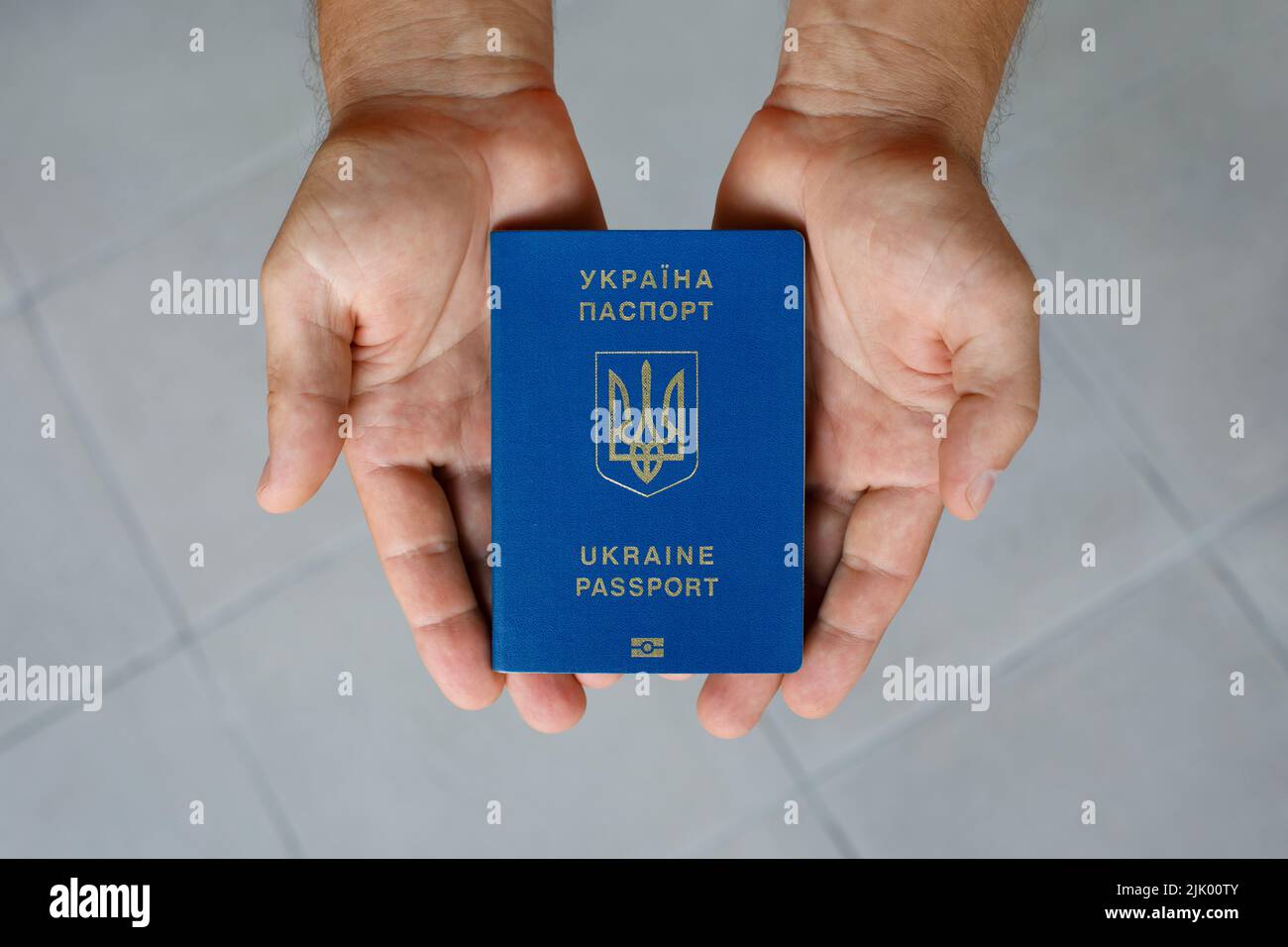 Passport of a citizen of Ukraine in a male hand on a gray background, close-up. Stock Photo