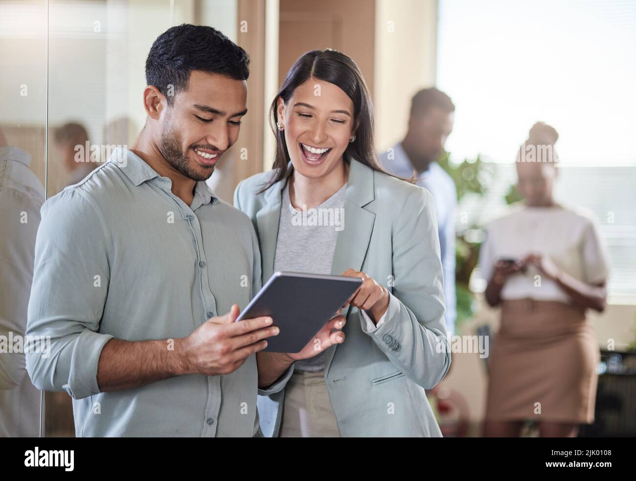 We should meet over coffee. two coworkers talking while using a digital tablet. Stock Photo