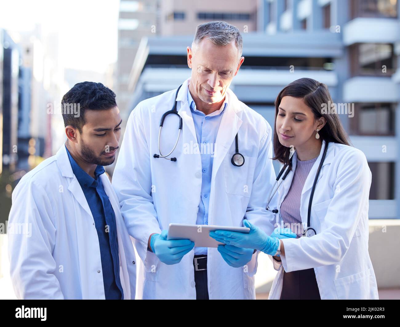 We cant put our heads into pillows. doctors using a digital tablet while outside in the city. Stock Photo