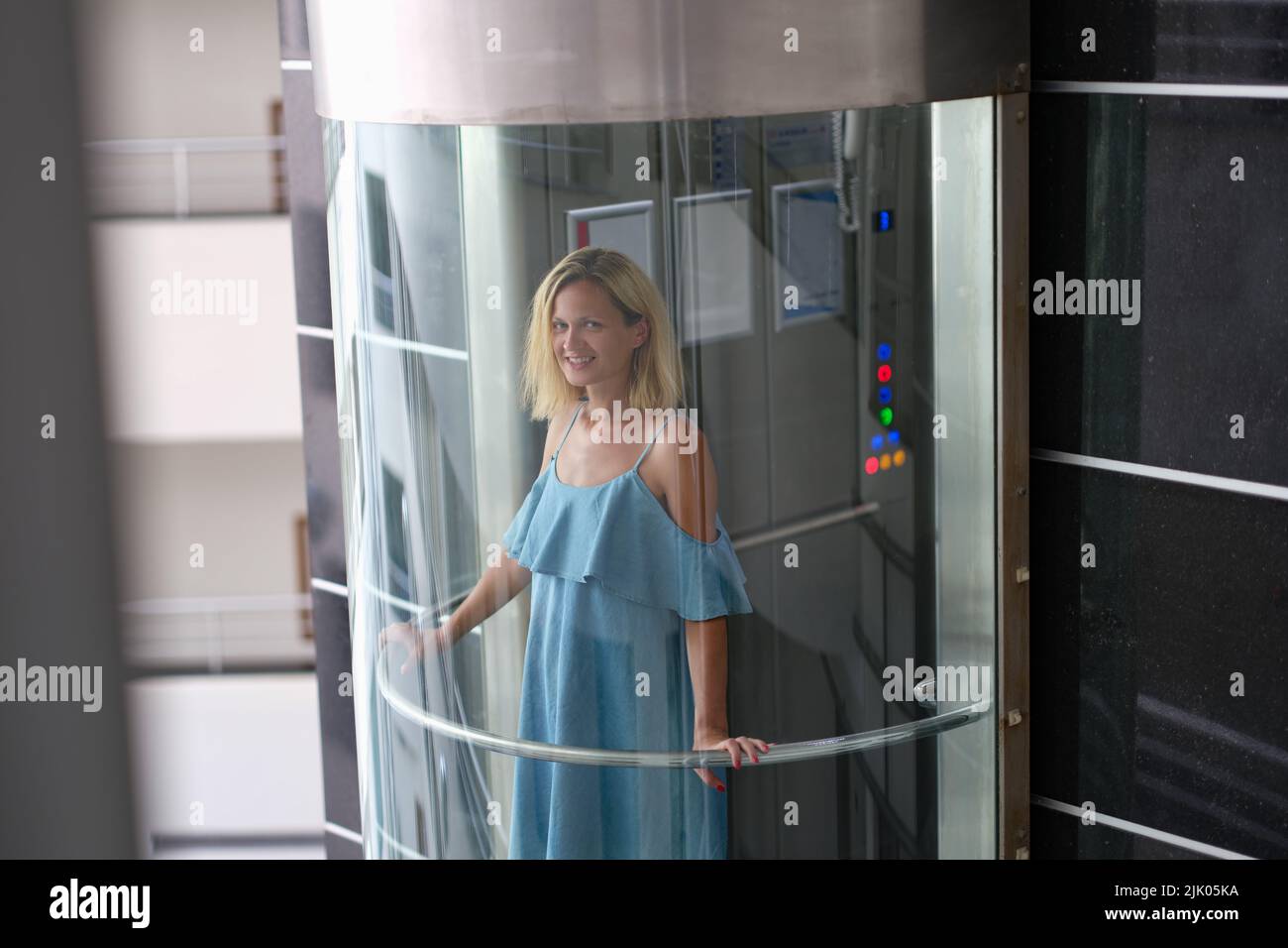 Beautiful smiling woman in transparent glass elevator Stock Photo