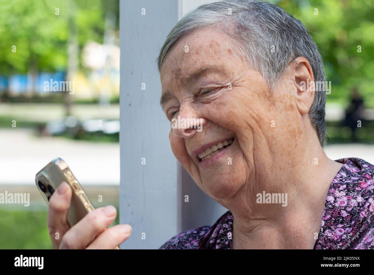 technology, old age and people concept happy senior woman with smartphone having video call on sunny day in park. Close-up portrait of laughing Senior Stock Photo