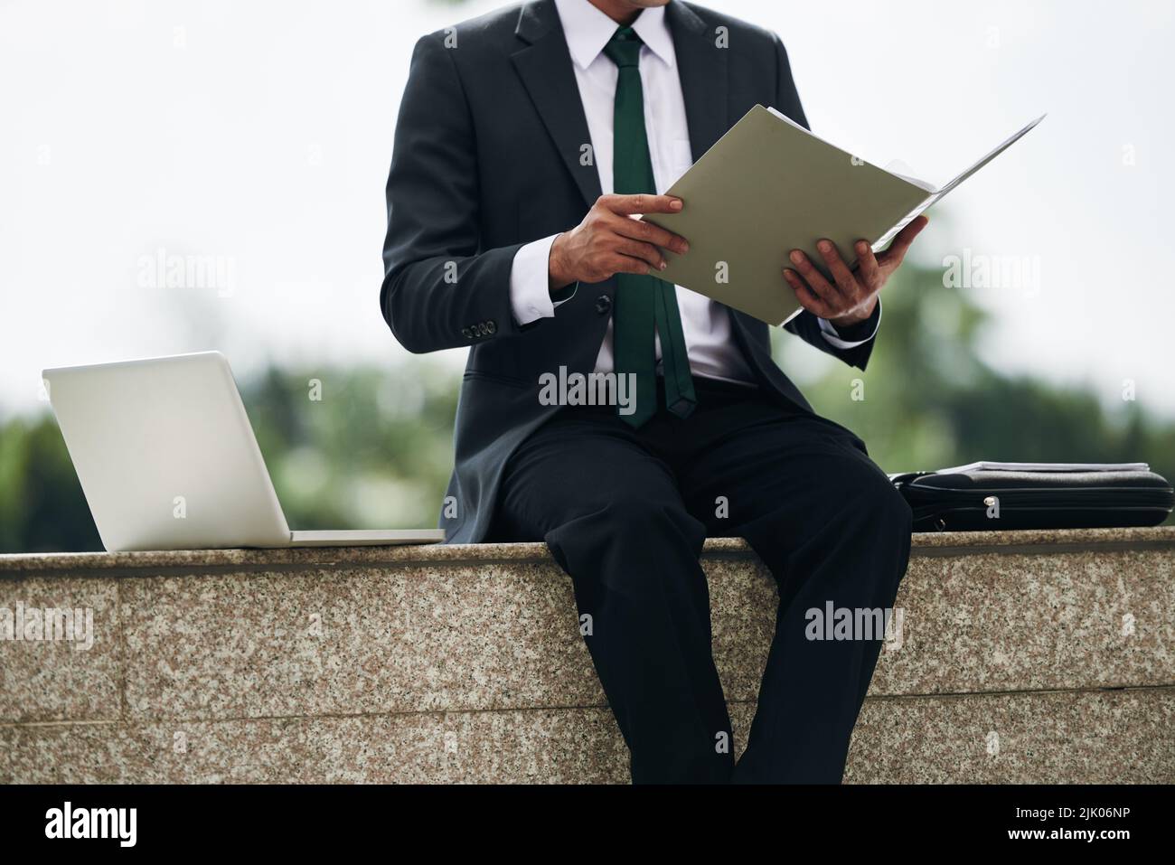 Entrepreneur checking business documents in folder when sitting outdoors Stock Photo