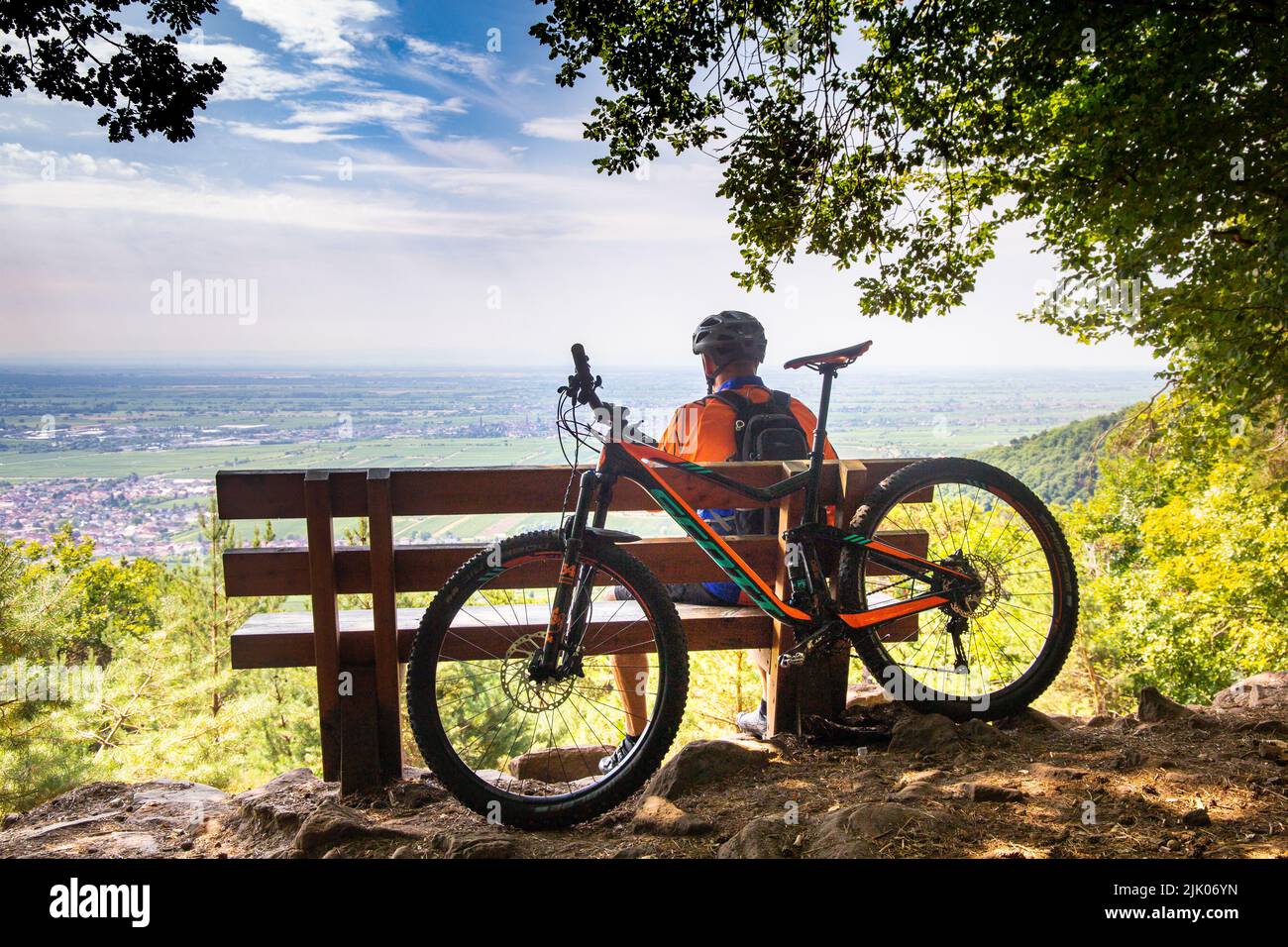 Mountain biker in the Palatinate Forest takes a break and looks out over the Rhine plain. The town in the foreground is Neustadt an der Weinstrasse (m Stock Photo