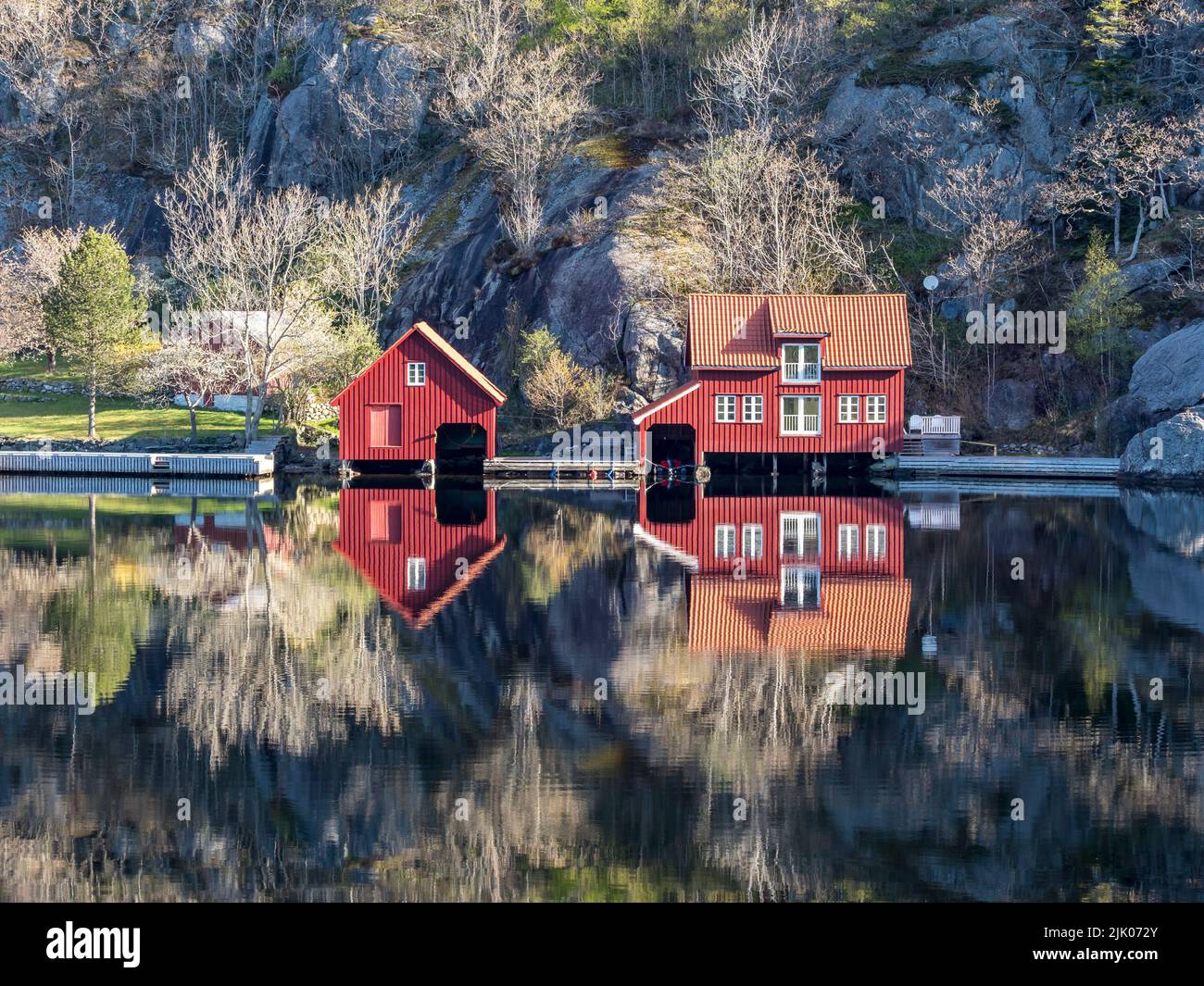 Fjord near Ana Sira at the norwegian southern coast, lonely houses at feet of a rock formation, Norway Stock Photo