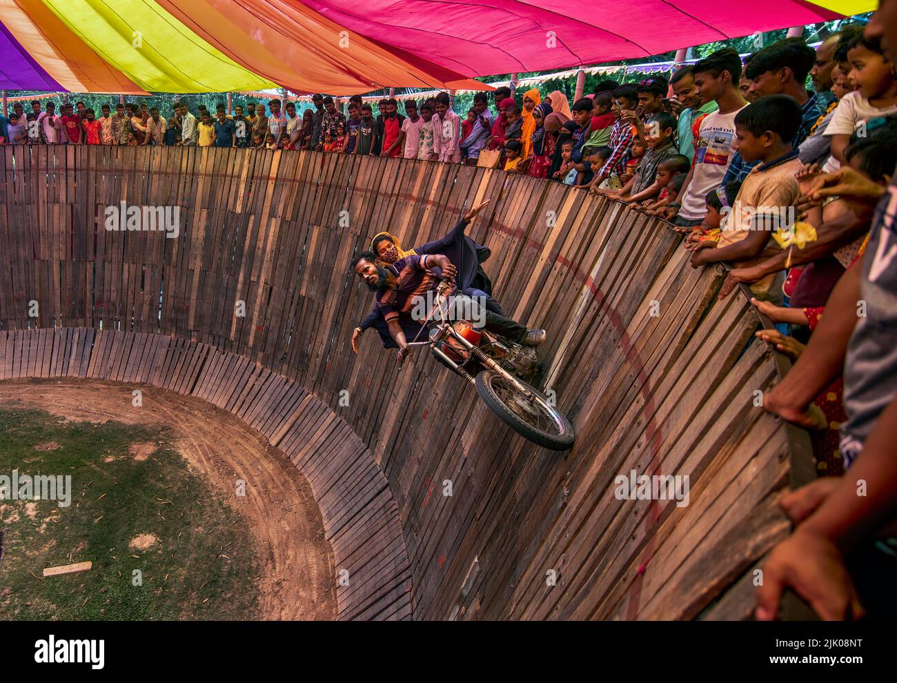 Daredevil motorcyclists ride around a steep 'wall of death' at 50 miles an hour with pillion behind Stock Photo