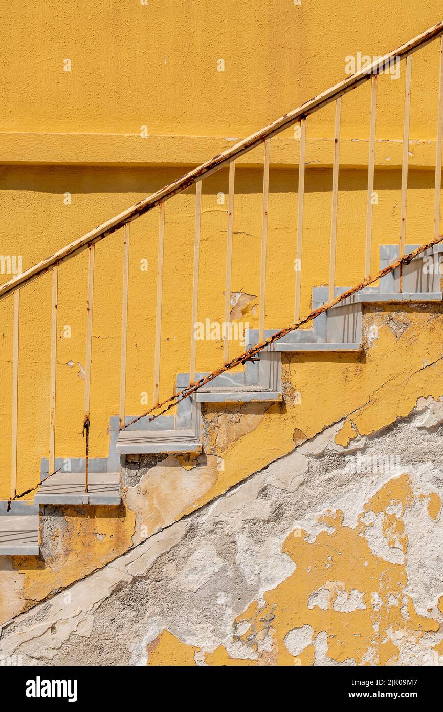 flight of yellow painted weather beaten distressed shabby chic steps or stairs made from concrete on the outside of a typically greek building, yellow Stock Photo