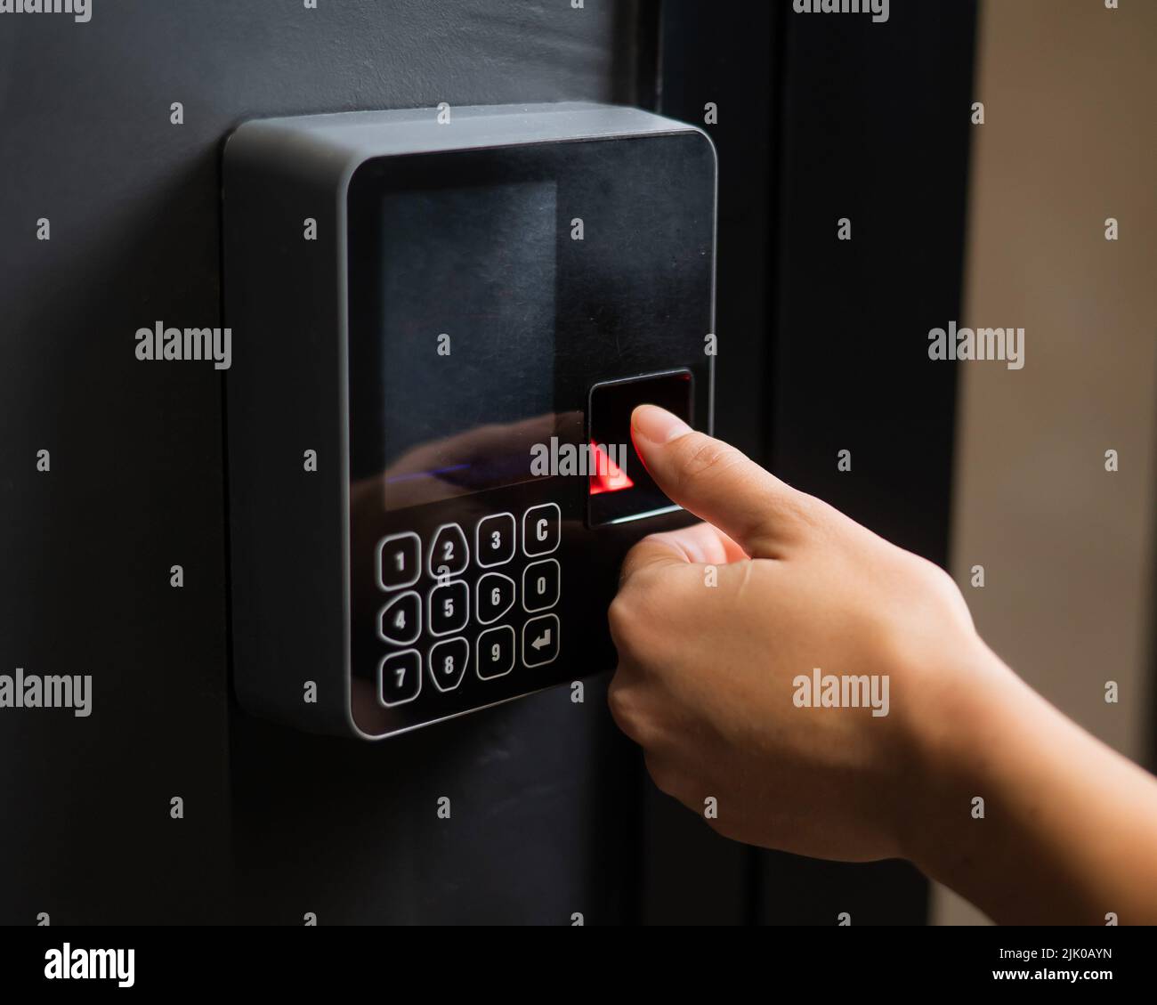 A woman opens the door with her fingerprint. Modern keyless entry lock.  Stock Photo