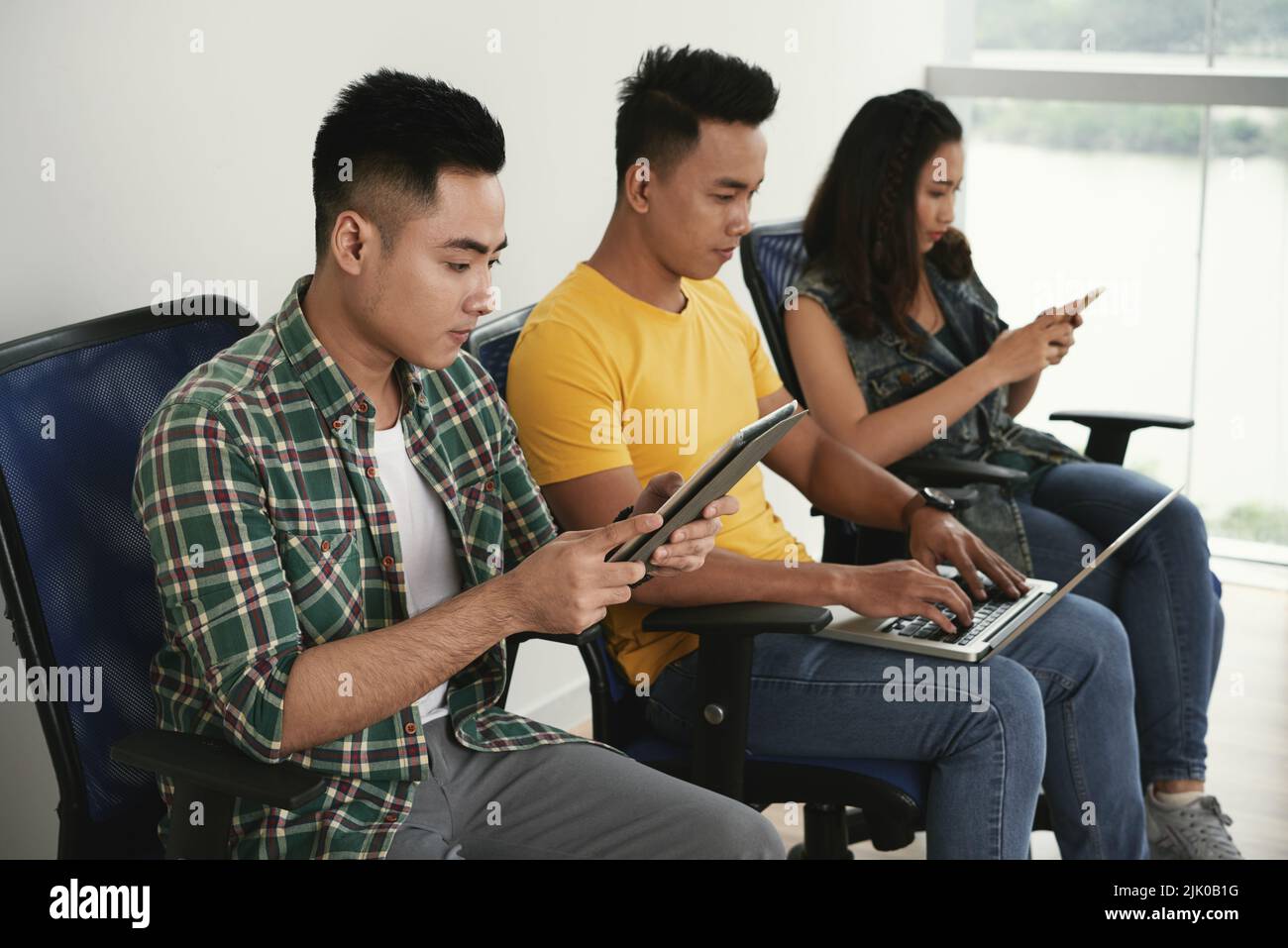 Vietnamese young people busy with work on various devices Stock Photo