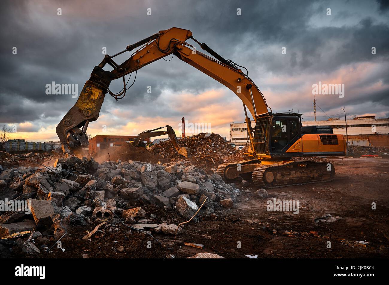 Modern crusher on excavator rigging dismantles concrete beam Stock