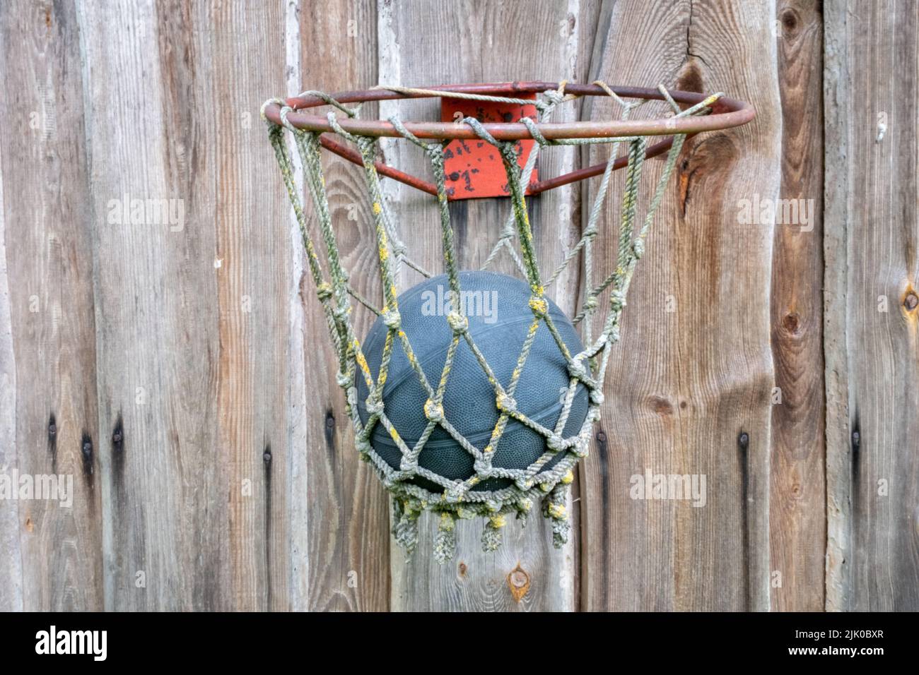A very old basketball hoop with a ball bolted to the wooden plank wall Stock Photo Alamy