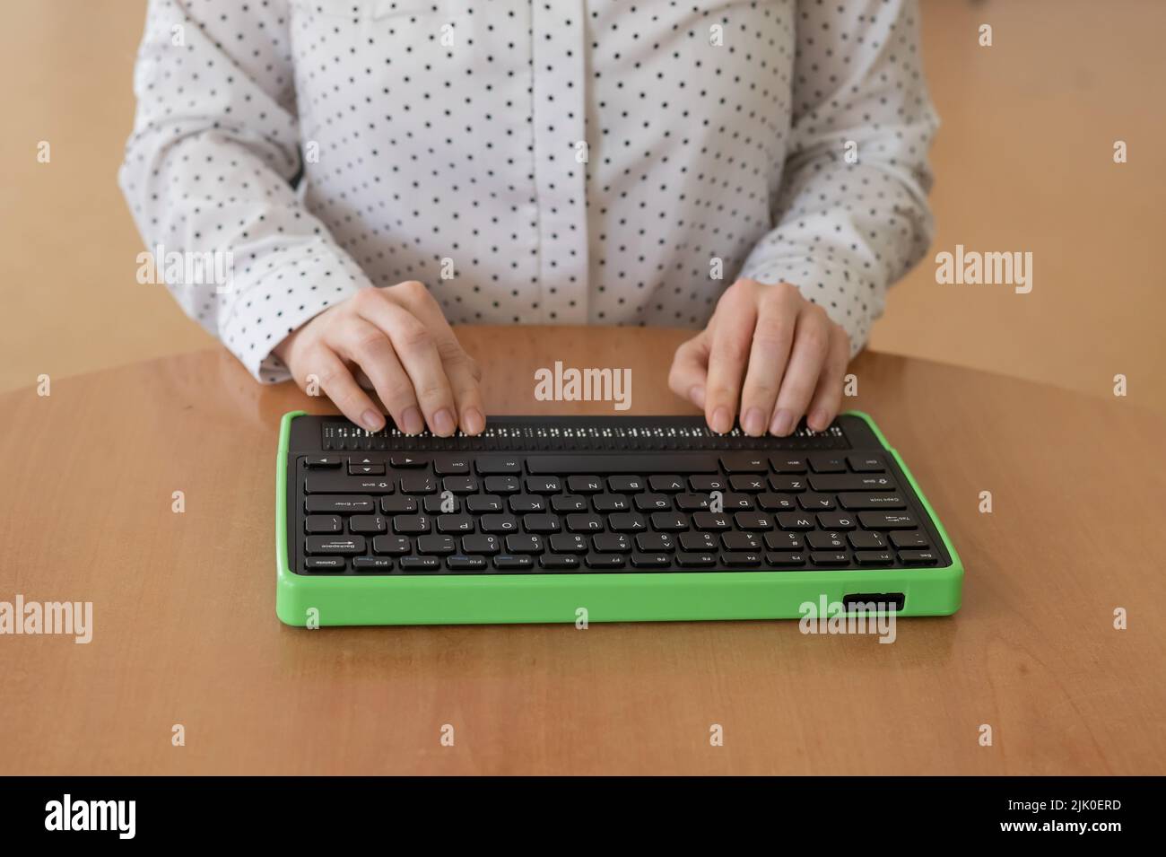 A blind woman uses a computer with a Braille display and a computer