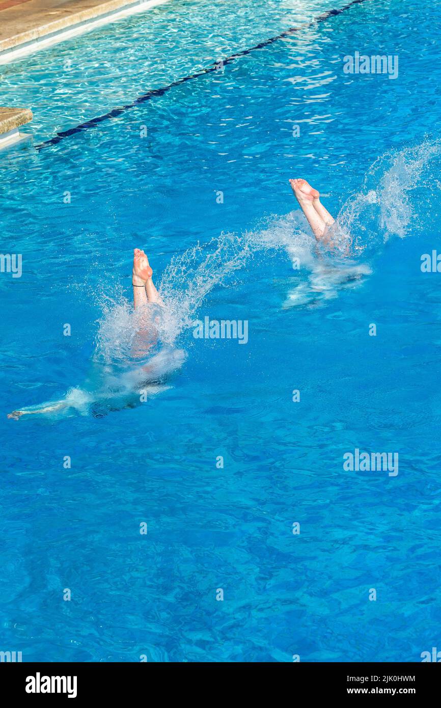 Aquatic pool diving girls pairs action water entry legs unrecognizable females overhead photo. Stock Photo