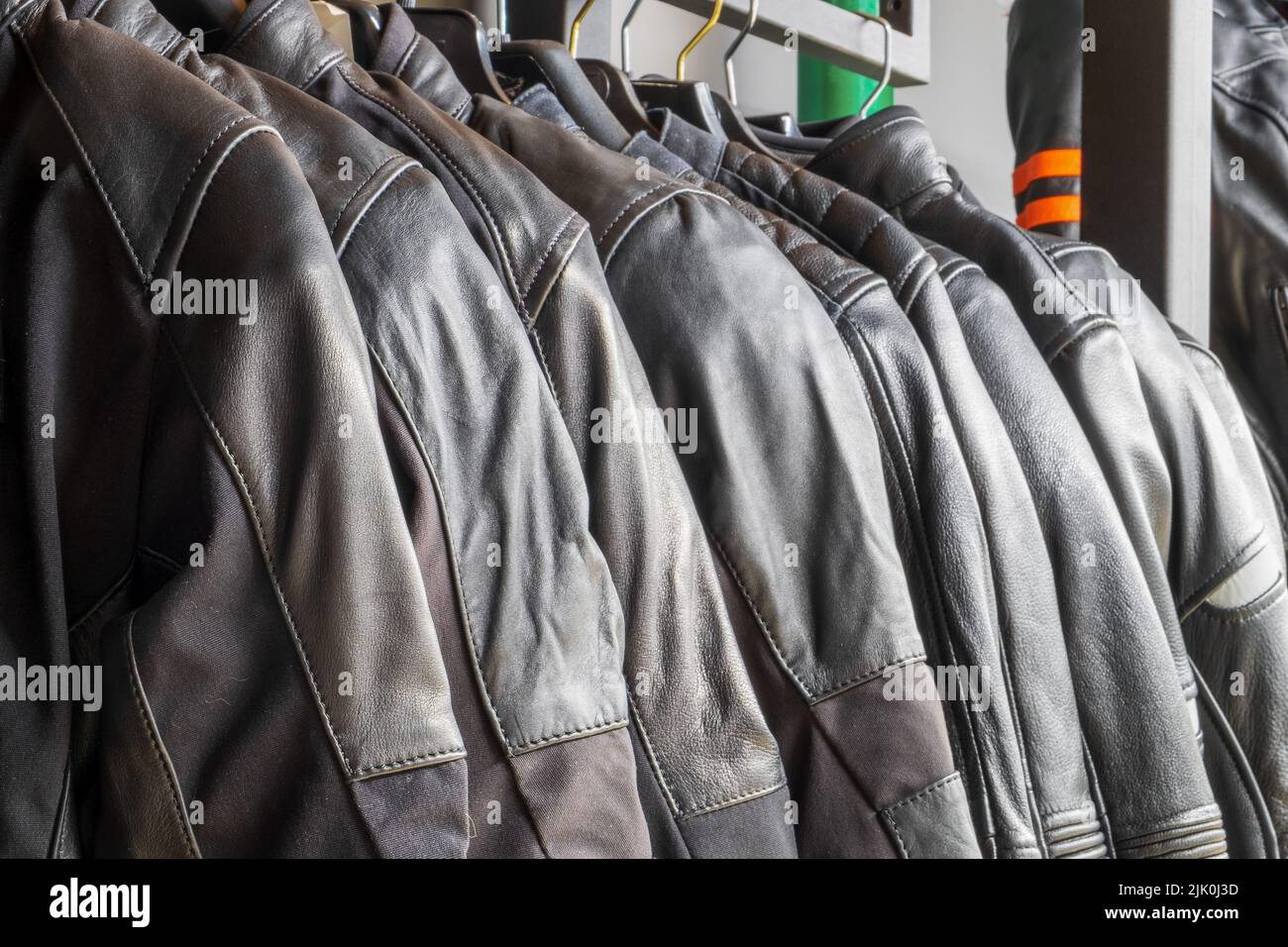 Black leather jackets for motorcyclists hang in a row close-up Stock Photo