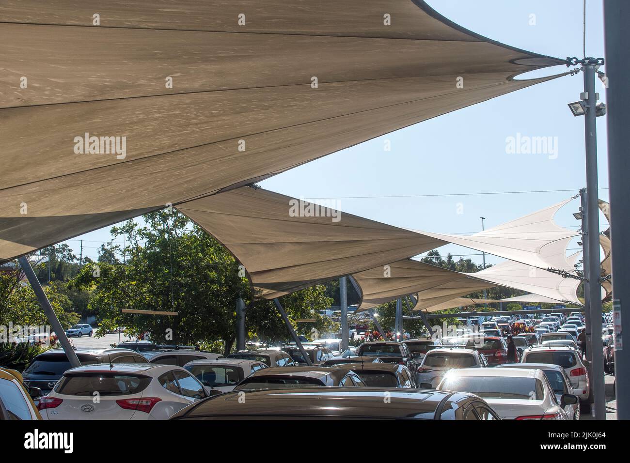 Shade sails over vehicles in car park at shopping centre on the Gold Coast, Queensland, Australia. Cars protected from strong sunlight and heat. Stock Photo