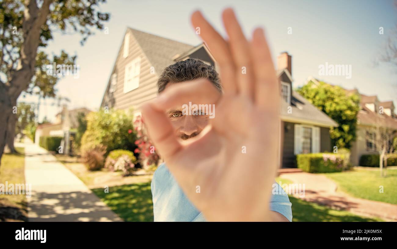 ok gesture closeup of unshaven guy standing near new house, ok Stock Photo