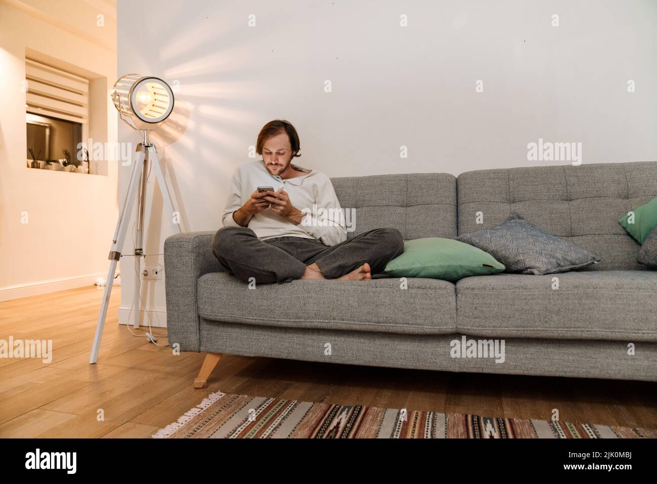 Ginger bristle man using mobile phone while resting on couch at home Stock Photo
