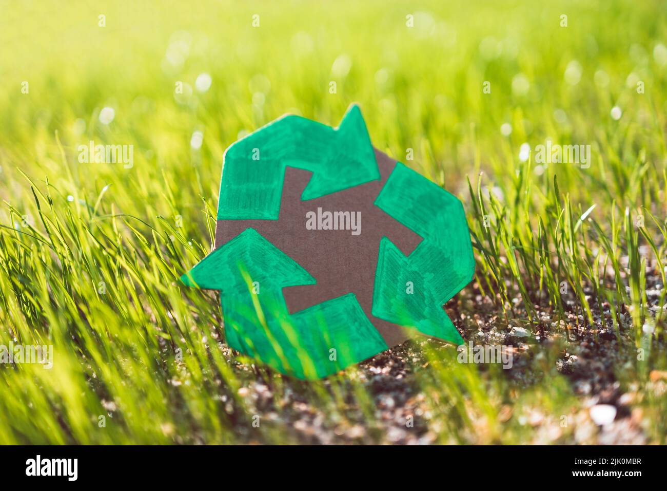 recycle sign hand drawn on cardboard over green grass under the ...