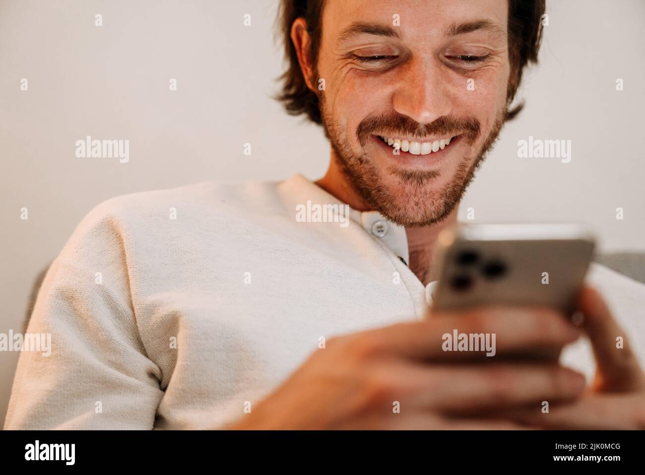 Ginger bristle man using mobile phone while resting on couch at home Stock Photo