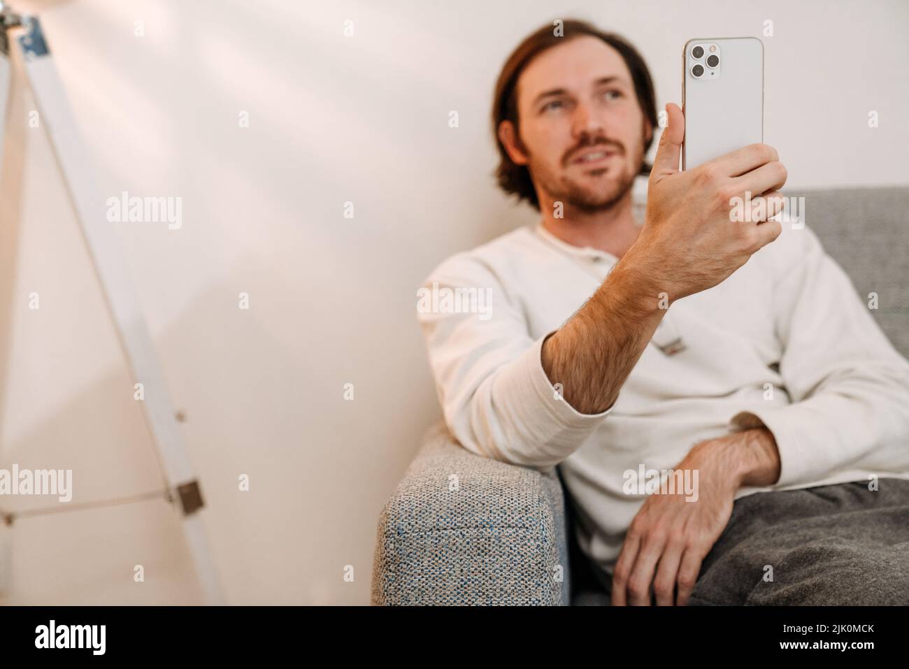 Ginger bristle man using mobile phone while resting on couch at home Stock Photo