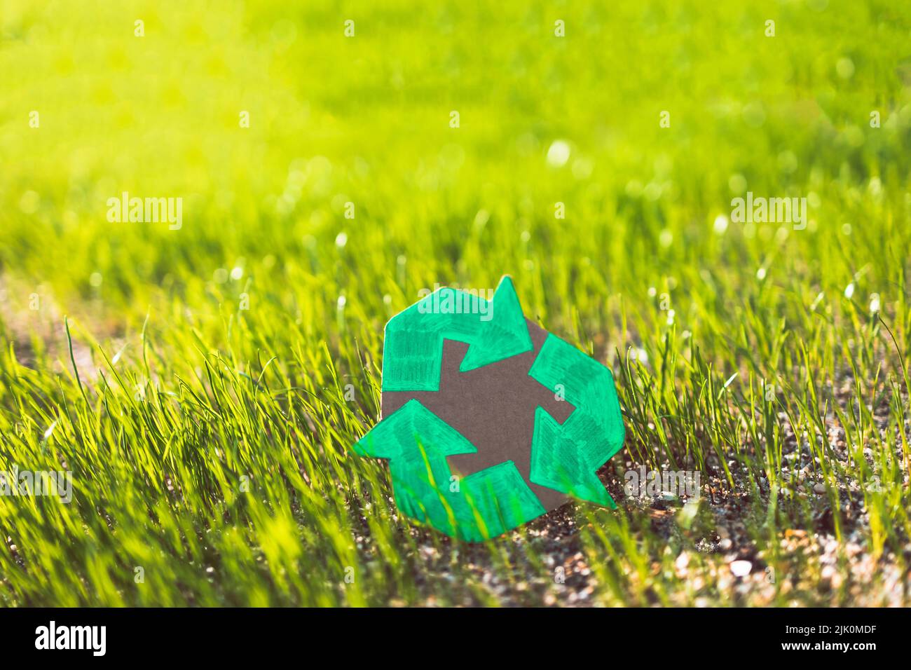 recycle sign hand drawn on cardboard over green grass under the ...