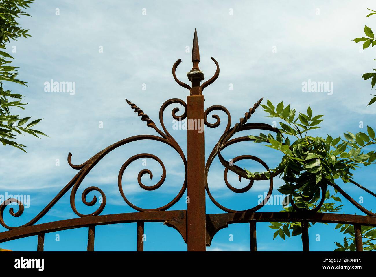 Closeup of a top part of an iron forged fence on the background of blue sky Stock Photo