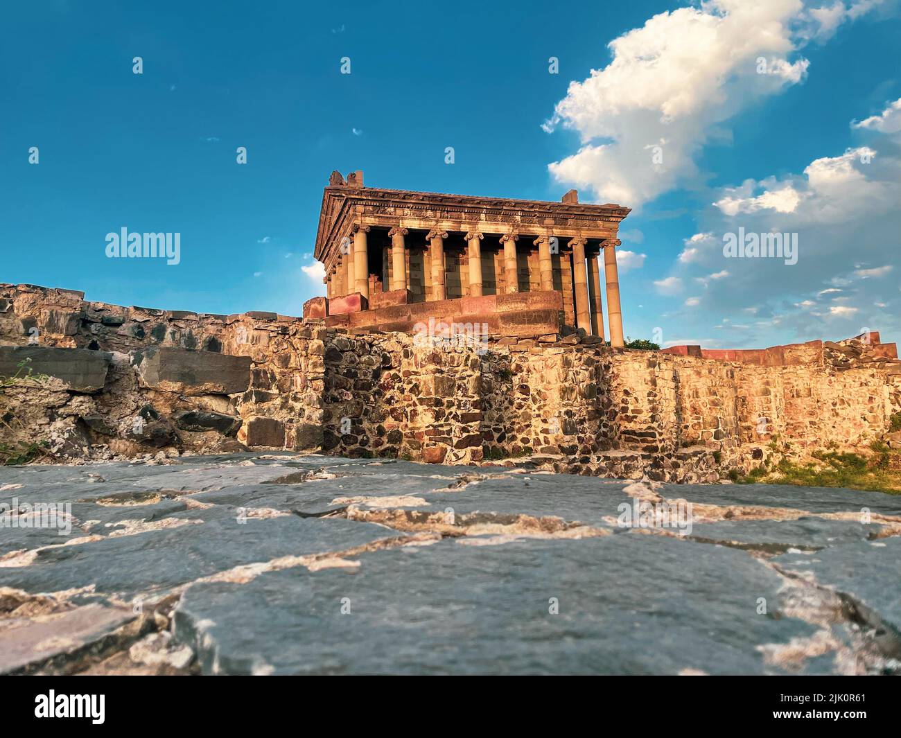 An ancient Hellenic temple with columns and a cloudy blue sky on the ...