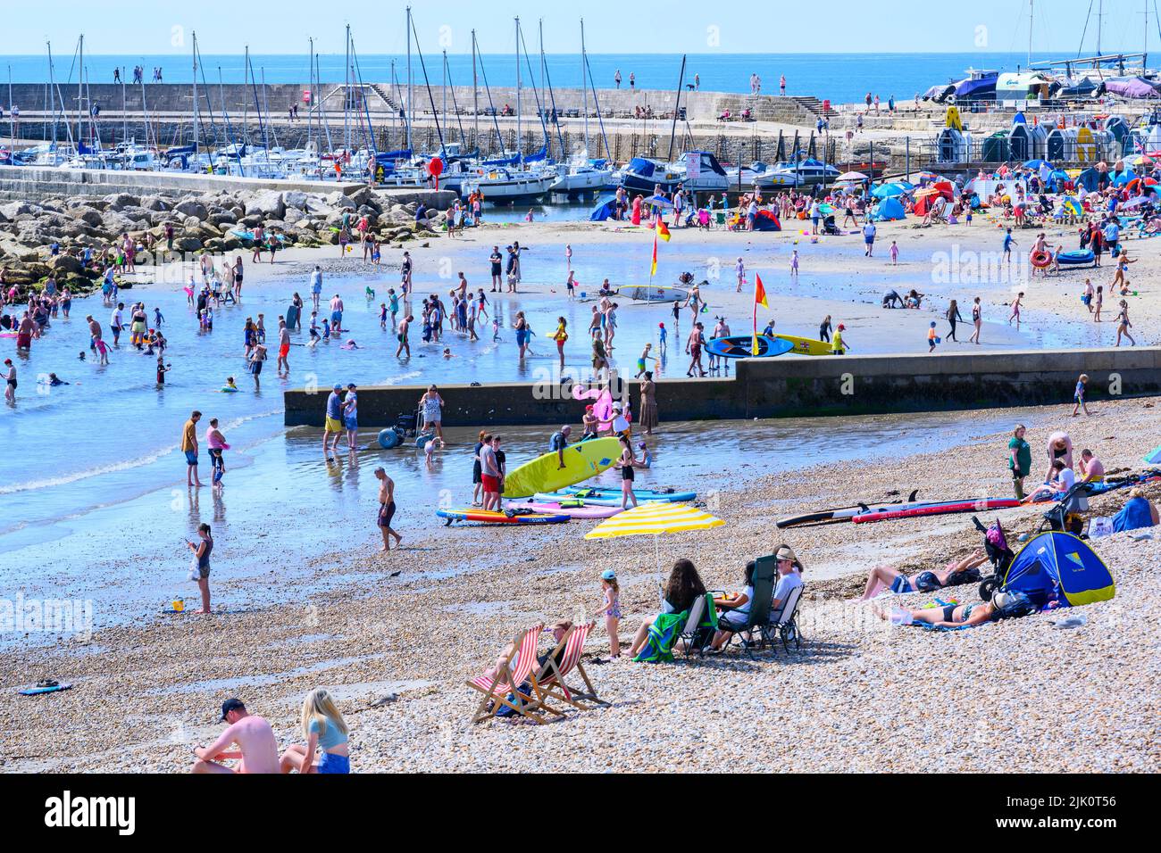 Lyme Regis, Dorset, UK. 29th July, 2022. UK Weather: Crowds of holidaymakers and sunbathers flock to the packed beach at the seaside resort of Lyme Regis to bask in scorching hot sunshine. Families, staycationers and sunseekers soaked up the lovely sunny weather as it made a welcome return in time for the weekend. Credit: Celia McMahon/Alamy Live News Stock Photo