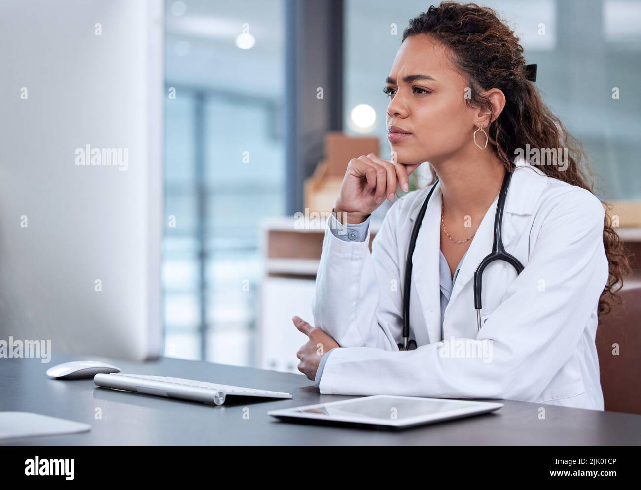 Something doesnt add up. a young female doctor using a computer in an office at work. Stock Photo