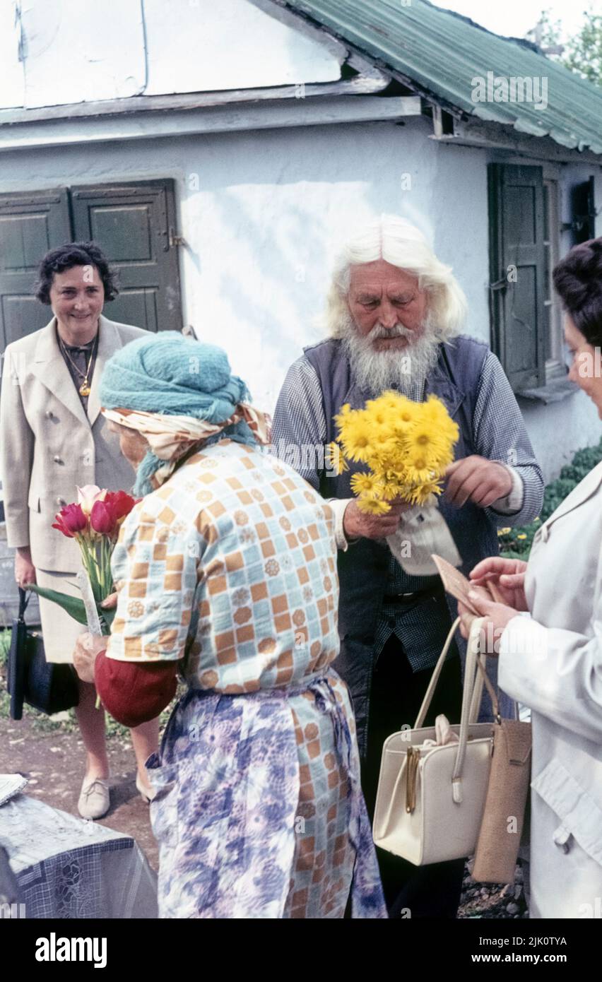 The Russian hermit Väterchen Timofej and his wife Natascha are selling flowers. Spring 1972, Oberwiesenfeld, Munich, Bavaria, Germany. Stock Photo