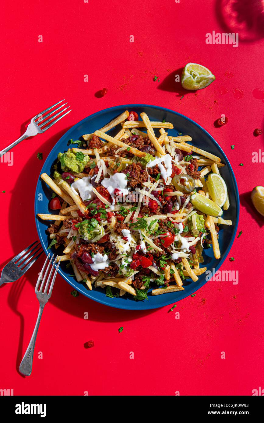 Loaded nacho fries with Mexican spiced beef, salsa, cheese, guacamole, sour cream and lime Stock Photo